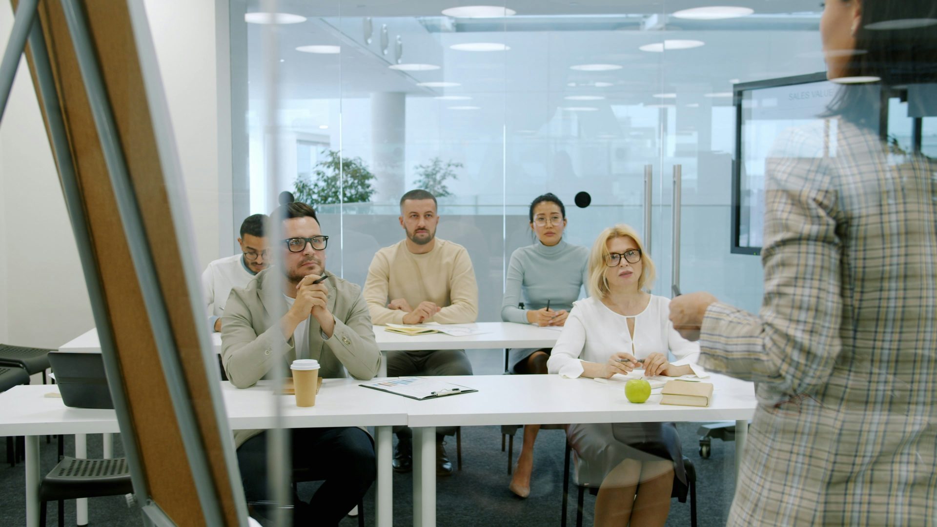 Des hommes et femmes d'affaires assistent à une présentation dans un bureau moderne.